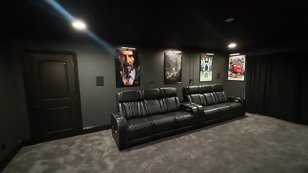 Dedicated home theater room with tiered leather recliner seating and framed posters lit by picture lights, Nashville TN