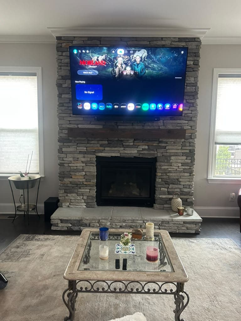 Large TV wall mounted on a stacked stone fireplace above a reclaimed wood mantel, Nashville TN